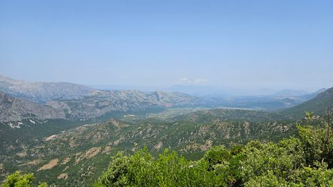 Mountain landscape with green hills and forested areas under a clear blue sky.